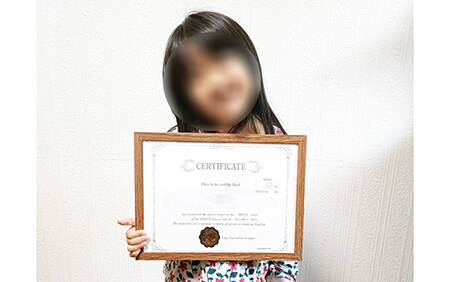英検Jr.で好成績を収めたことを証明する賞状を手に、笑顔を見せる保育園年少組の女の子