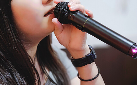 マイクを手にボイストレーニングをする若い女性